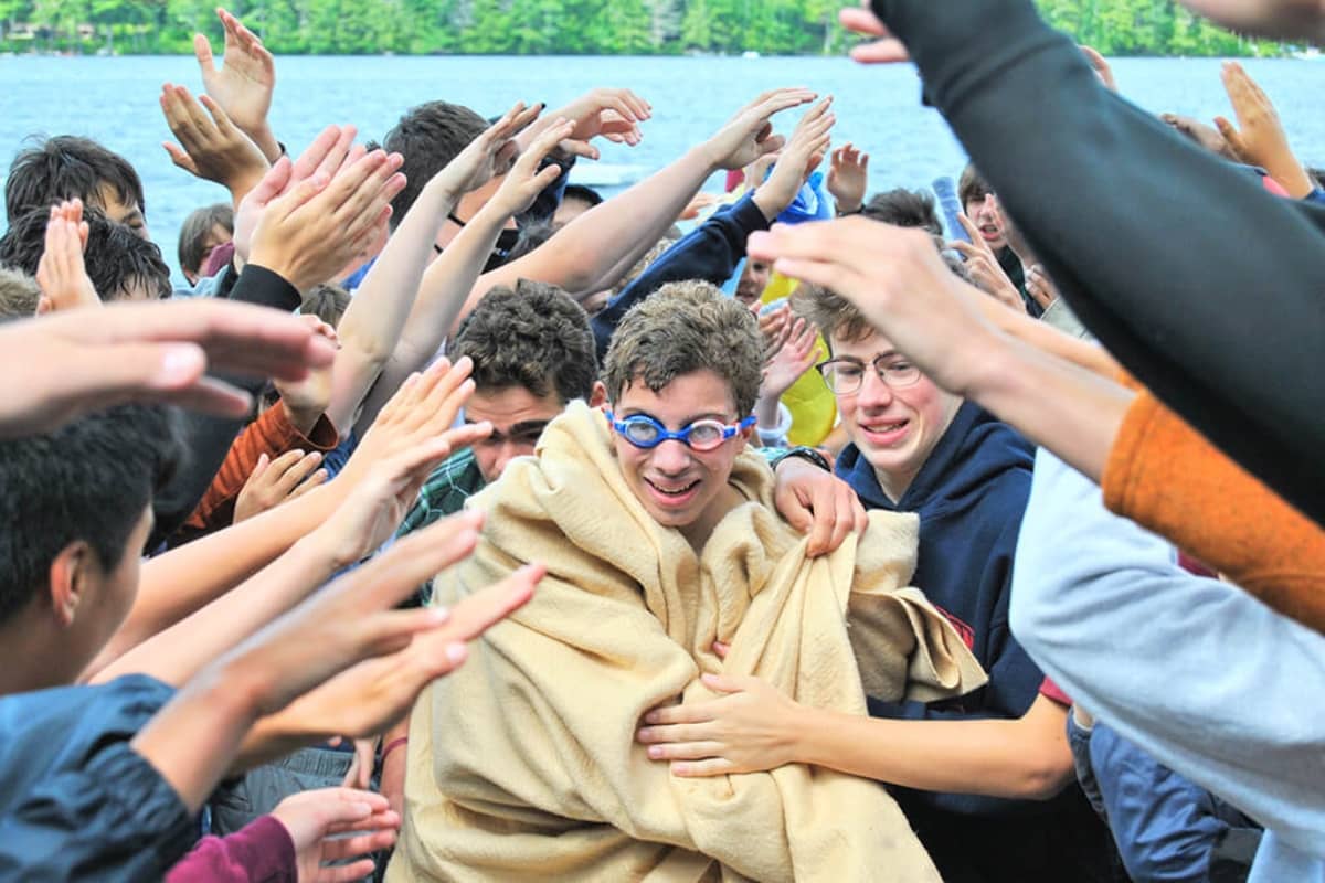 Kids huddling around boy who just got out of lake