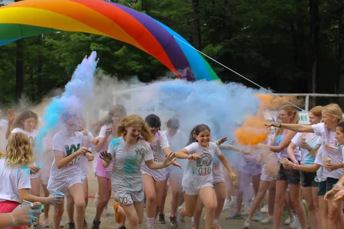 Campers running with rainbow in the back at Camp Waukeela