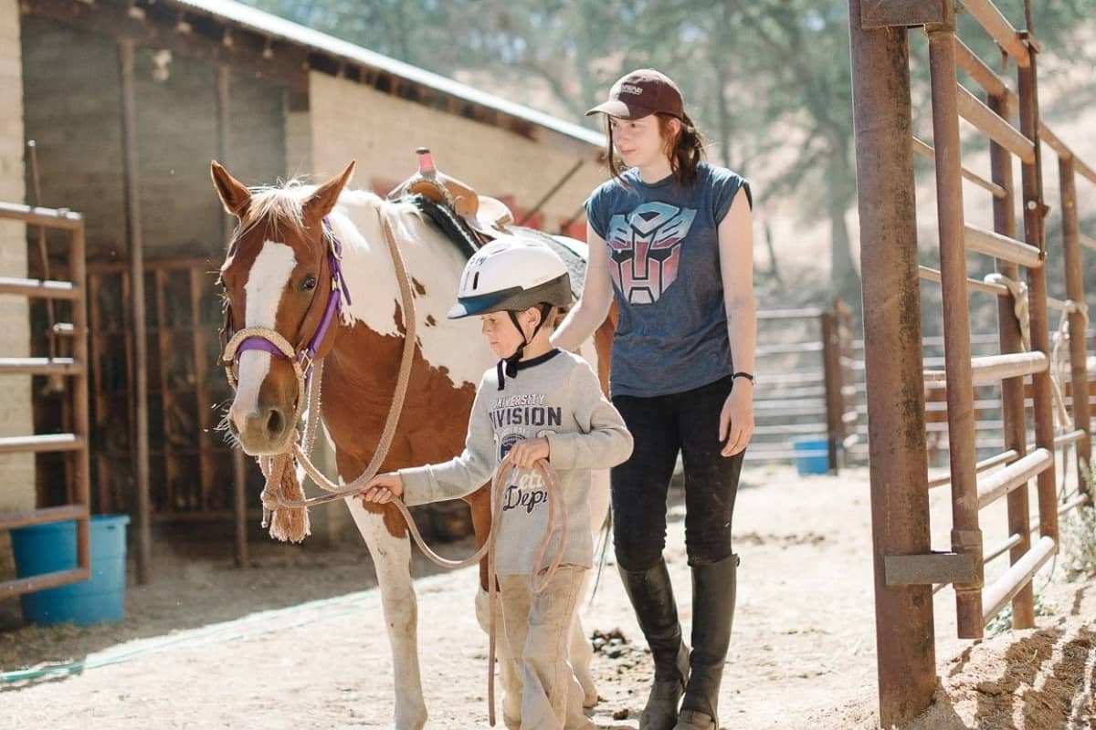 Boy going horseback riding with his instructor nearby