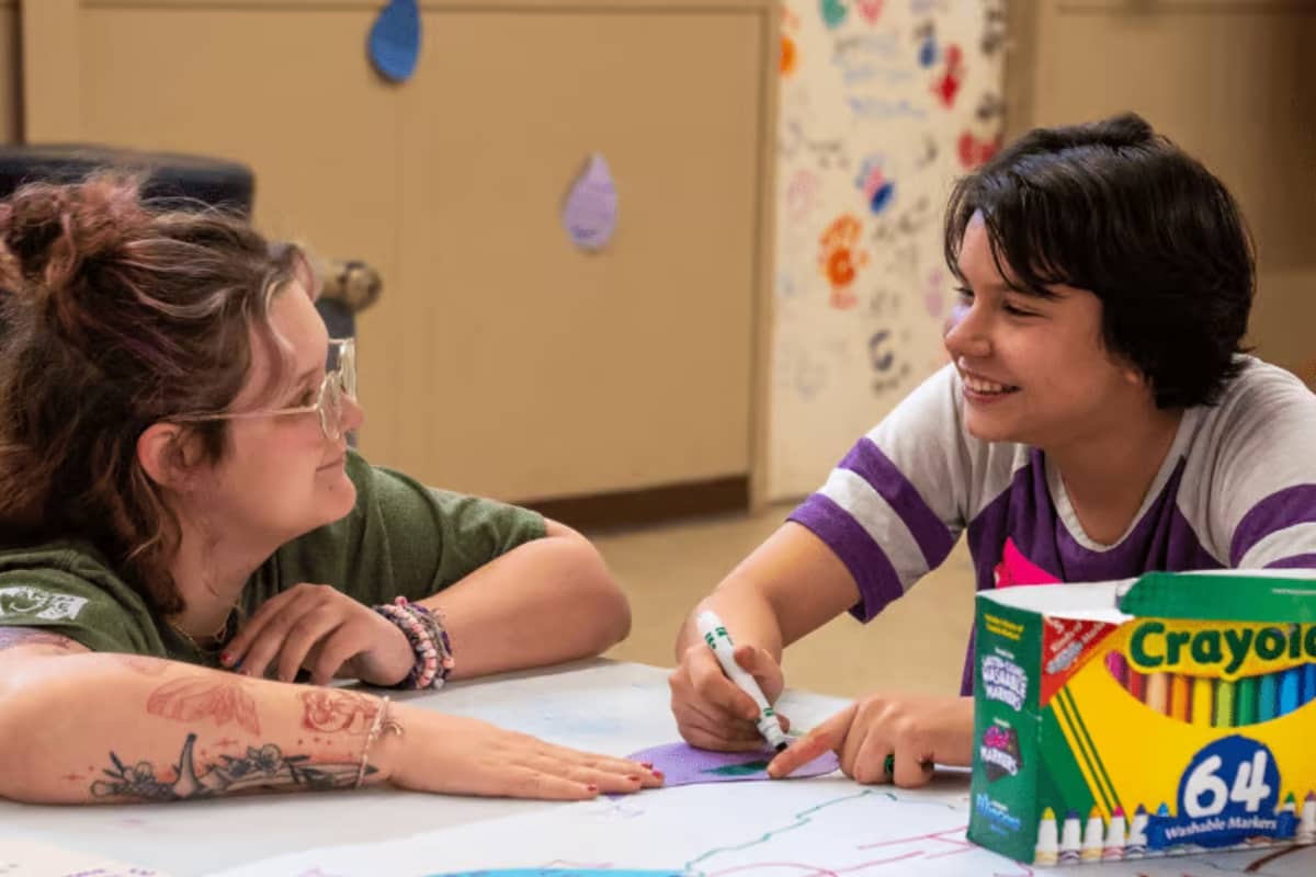 Camper and counselor coloring a book