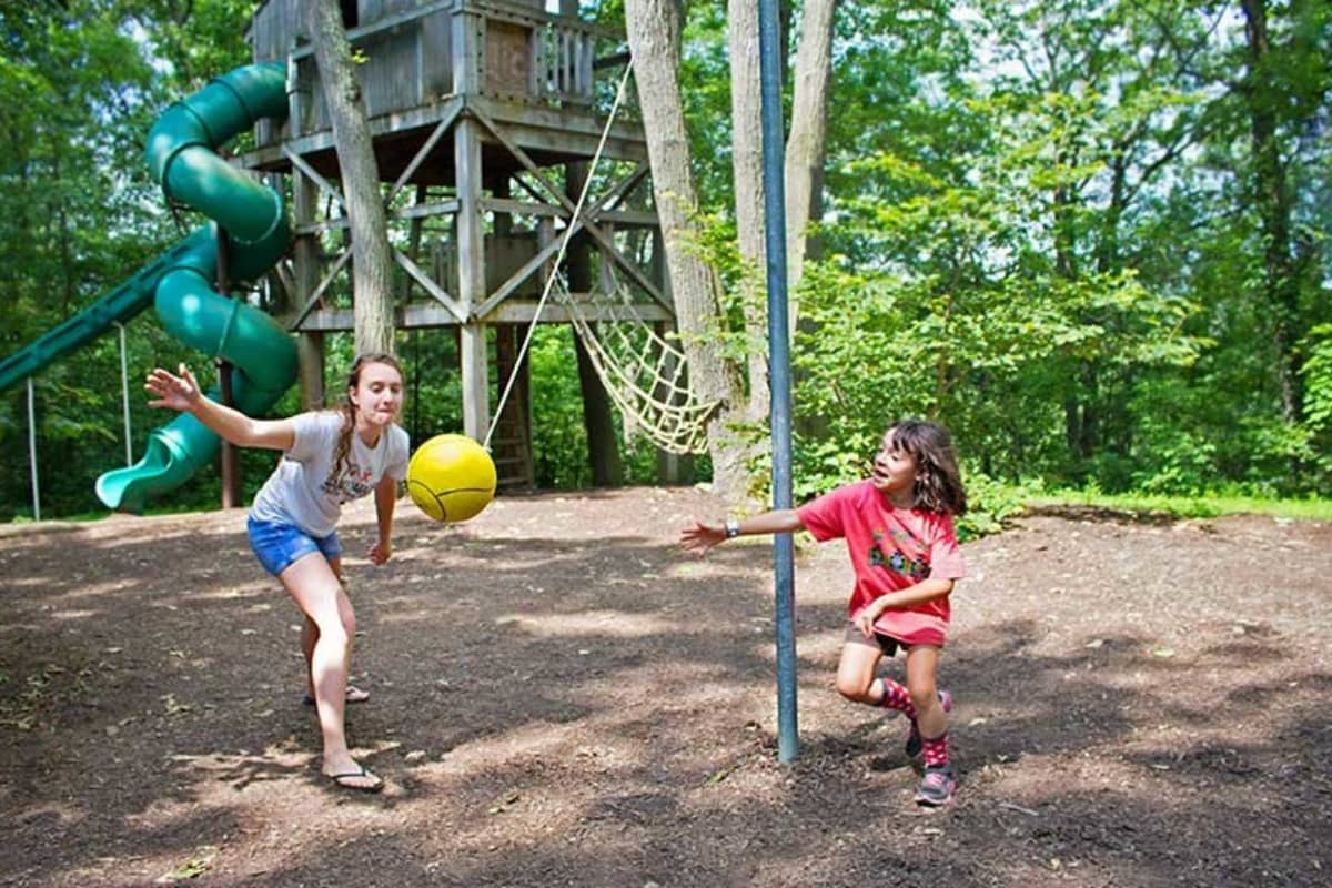 Girls swinging ball tied to a rope around