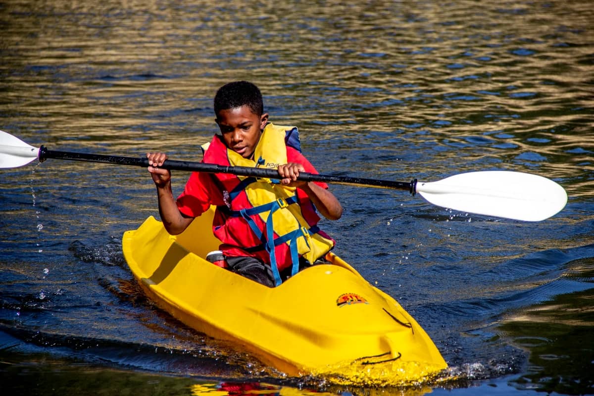 Young boy paddling in a lake