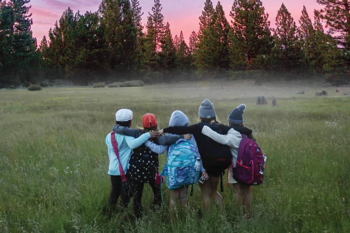 Group of campers hugging and looking at the wilderness