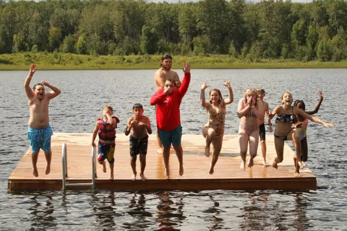 Kids jumping into water at lakeside camp