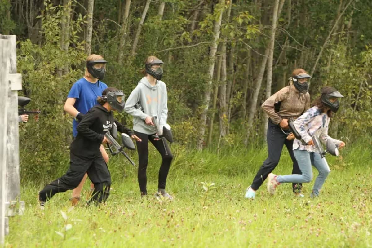 Campers playing paintball with safety equipment