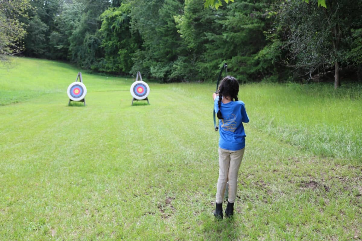 Young girl shooting bow and arrow